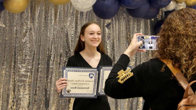 365英国上市杜波依斯分校 student Savannah Ross pauses with her awards for a photo, 由家庭成员拍摄, 在PAW中心举行的表彰和颁奖宴会上.